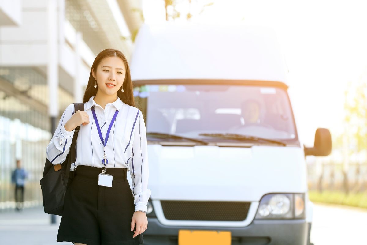 An Asian girl on the way with a bag smiling and going to work